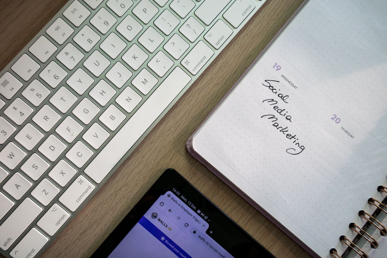 Vue de dessus d’un clavier, d’un agenda avec une note de marketing sur les médias sociaux, et d’une tablette sur un bureau.